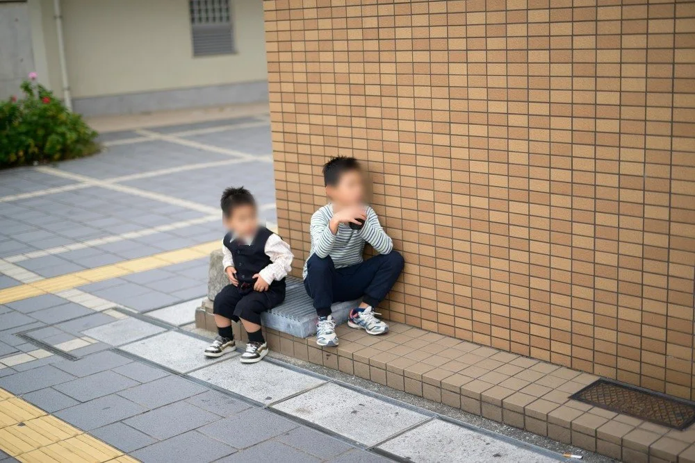 벽돌 벽 앞 턱에 앉은 아이 둘