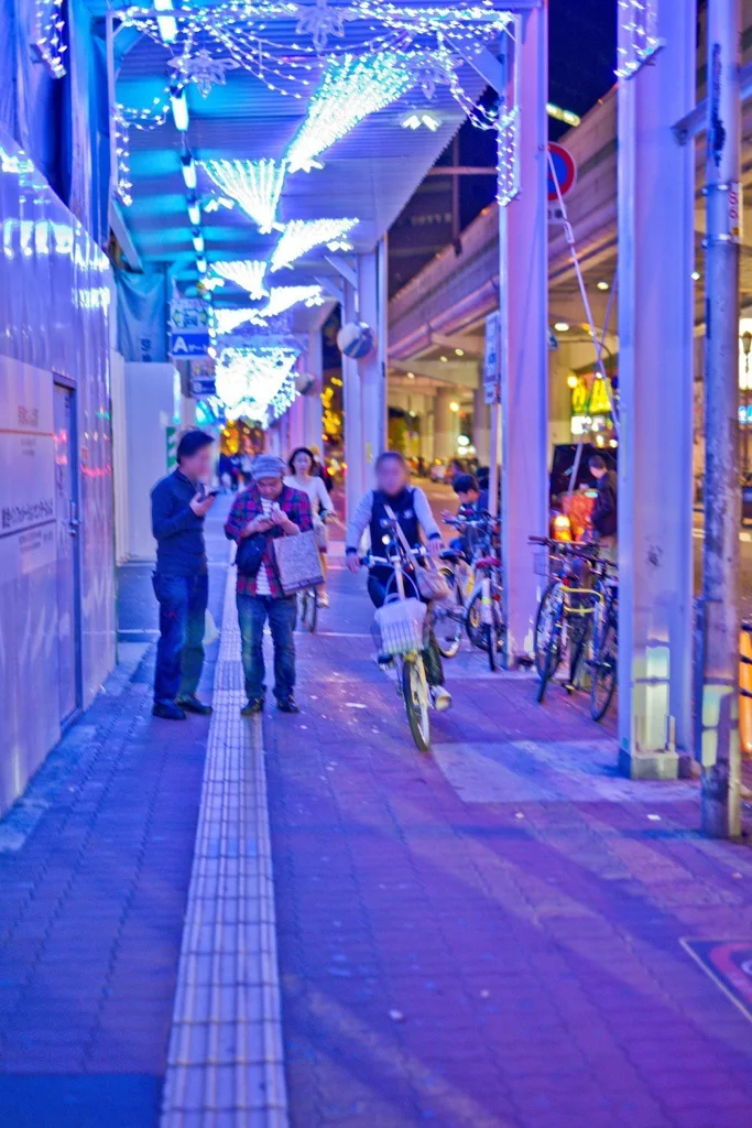 파란 조명이 걸린 지붕 덮인 길, 점자 블록과 자전거(세로 사진, 얼굴 가림)