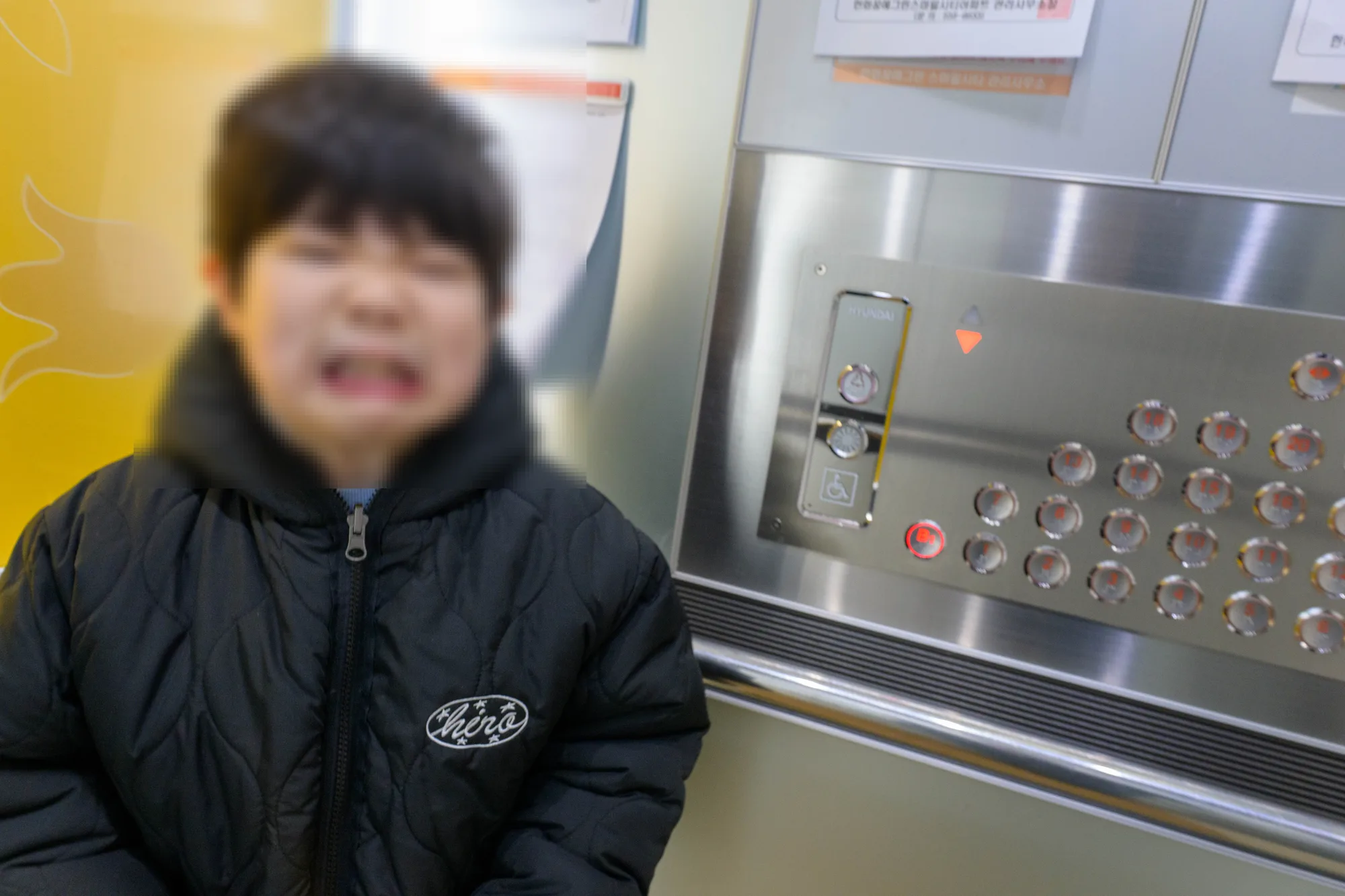엘리베이터 앞에서 표정을 짓는 아들