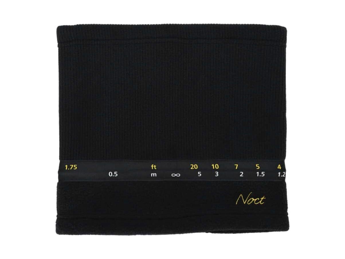 거리 눈금과 Noct 자수가 들어간 검정 렌즈 넥워머를 펼쳐 놓은 모습