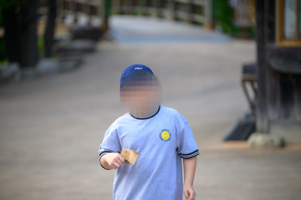 흐린 길을 배경으로 손에 쥔 것을 내밀며 다가오는 아이