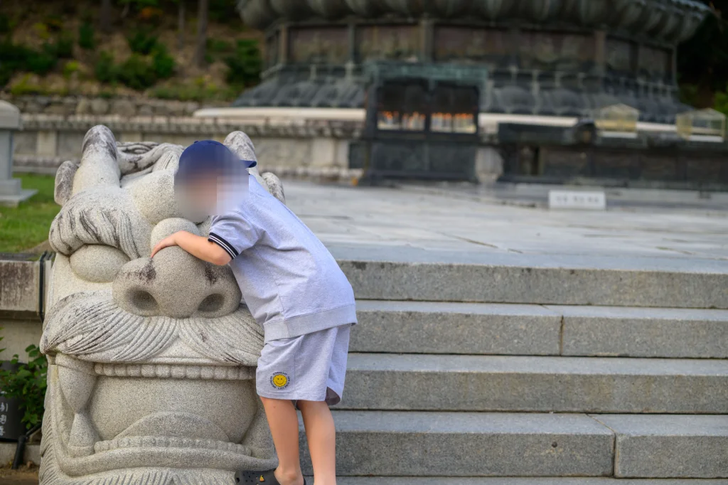 돌짐승 석상의 머리를 두 팔로 끌어안은 아이