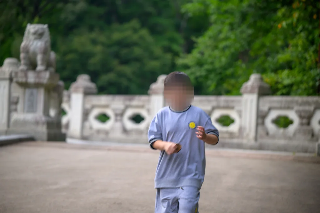 돌다리 위에서 카메라 쪽으로 달려오는 아이, 흐려진 난간과 돌짐승