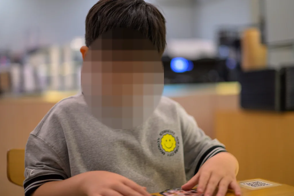 식당 테이블에서 카드를 펼쳐 보는 아이