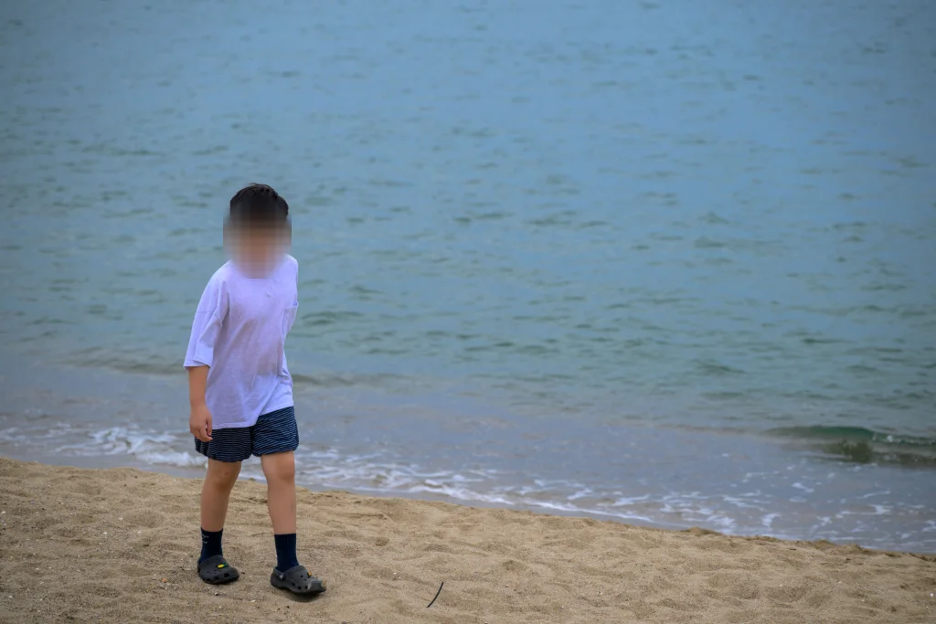 파도가 밀려드는 물가에 선 아이