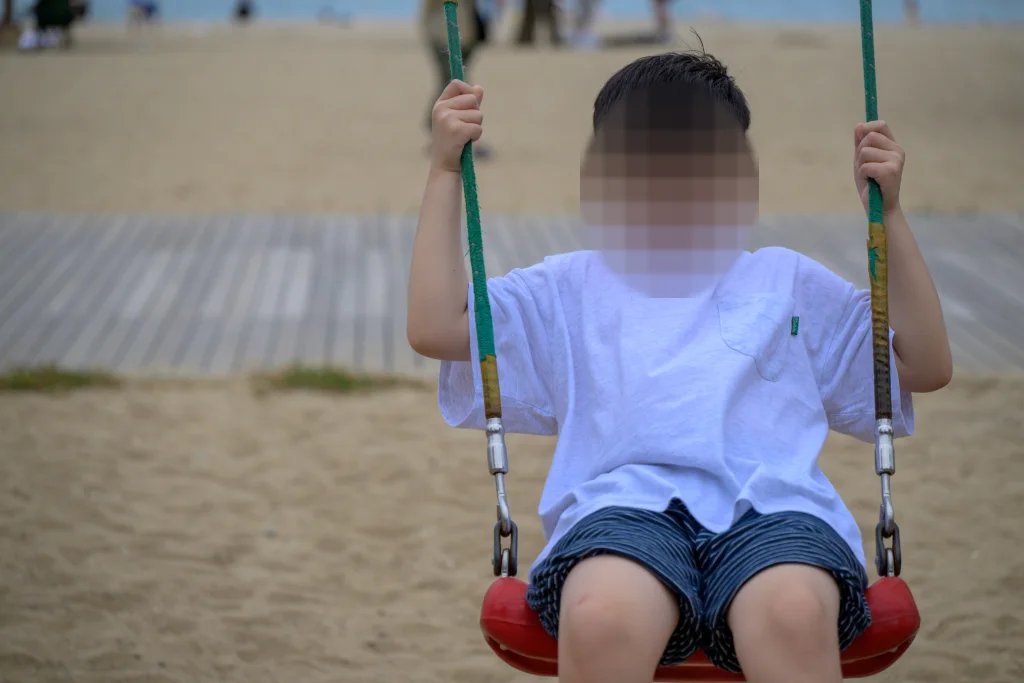 그네 줄을 두 손으로 잡고 앉은 아이를 정면에서 가까이 찍은 사진
