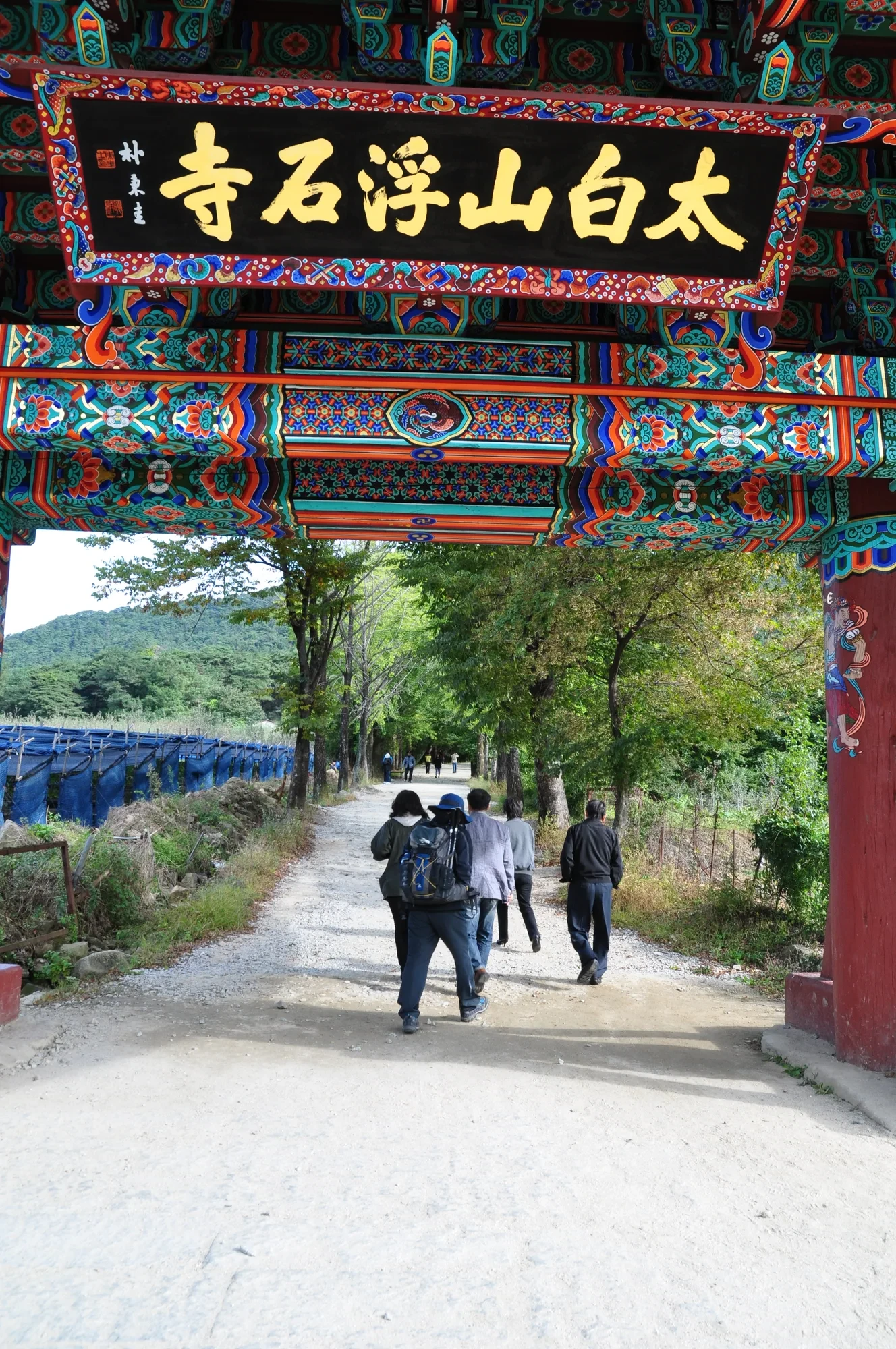 '太白山浮石寺' 현판이 걸린 단청 문과 문 너머 자갈길을 걷는 사람들