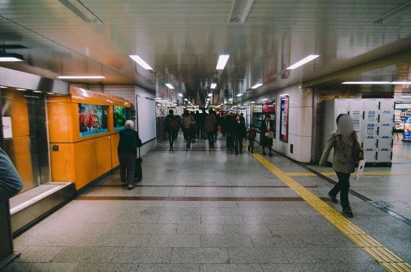 실내 통로를 걸어오는 사람들과 바닥의 노란 점자 블록