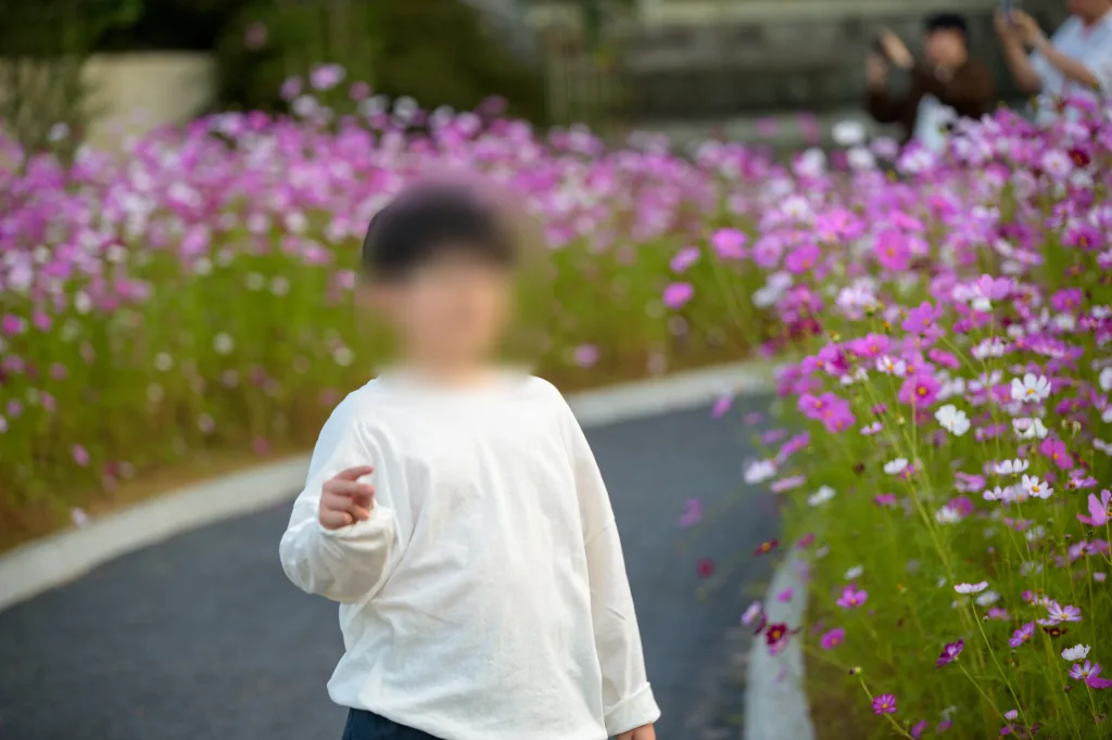 꽃밭 앞에서 한 손을 앞으로 내민 아들