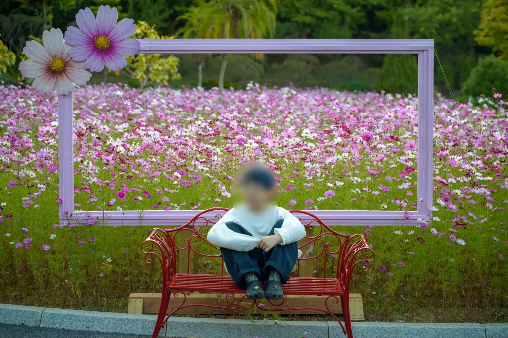 빨간 벤치 위에서 다리를 모아 올려 앉은 아들