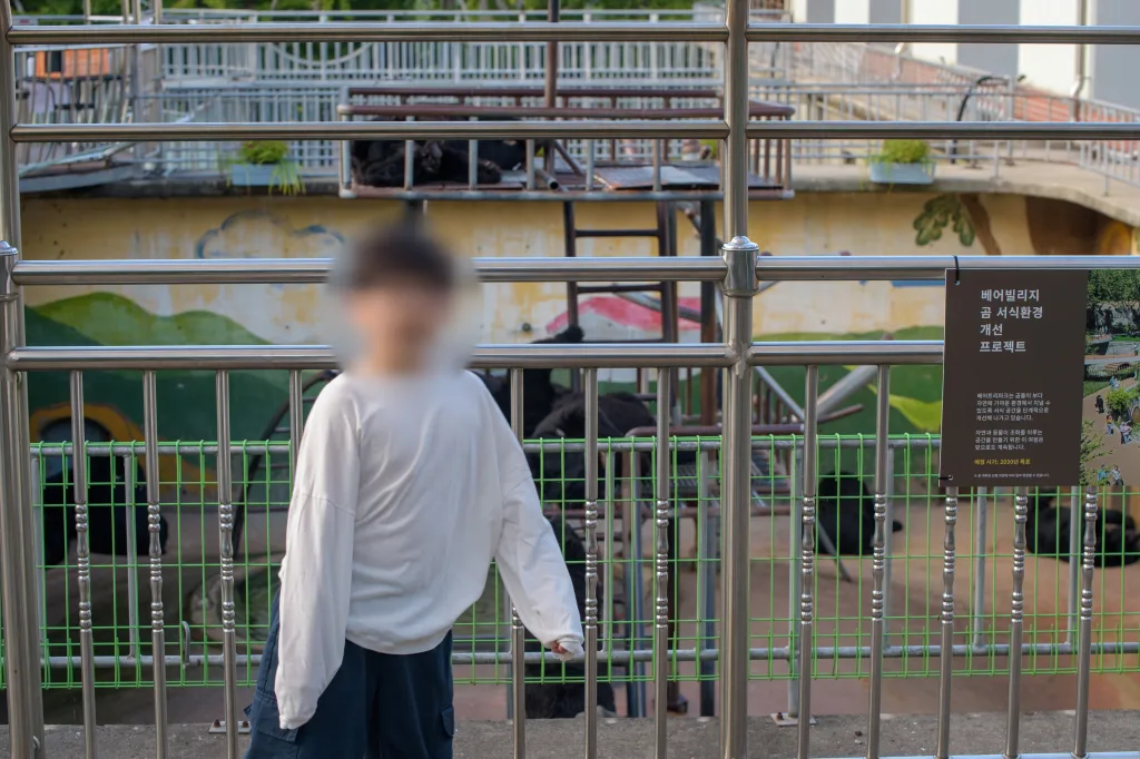 사육장 난간 앞에 정면으로 선 아들과 오른쪽 안내판
