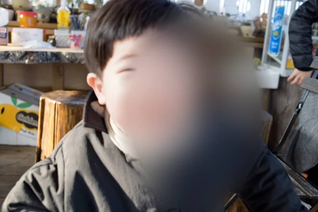 카메라 앞까지 다가온 아이의 머리와 어깨를 가까이서 찍은 사진(얼굴 가림)