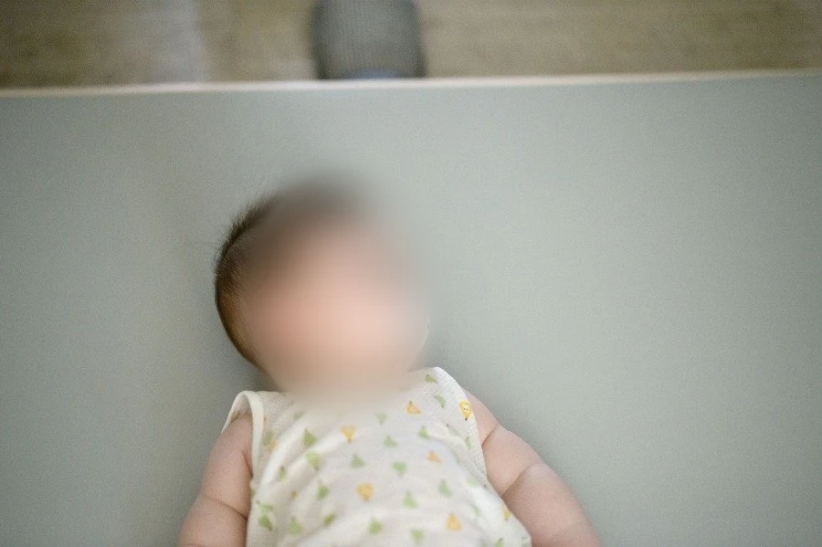 연한 색 바닥에 누운 아기와 입에 문 쪽쪽이, 얼굴을 가림