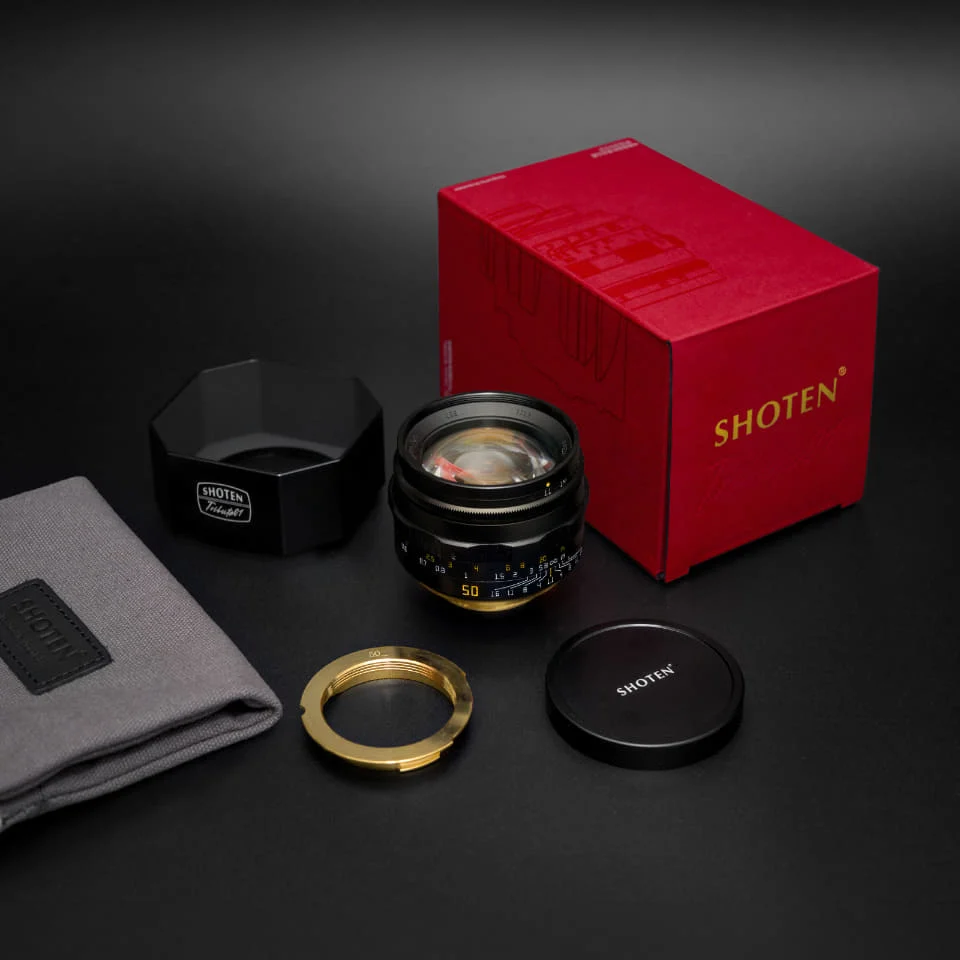 SHOTEN TRIBUTE 01 블랙 렌즈와 빨간 상자, 각진 후드, 금색 L39-M 변환 링, 앞 캡, 보관 주머니를 늘어놓은 구성품